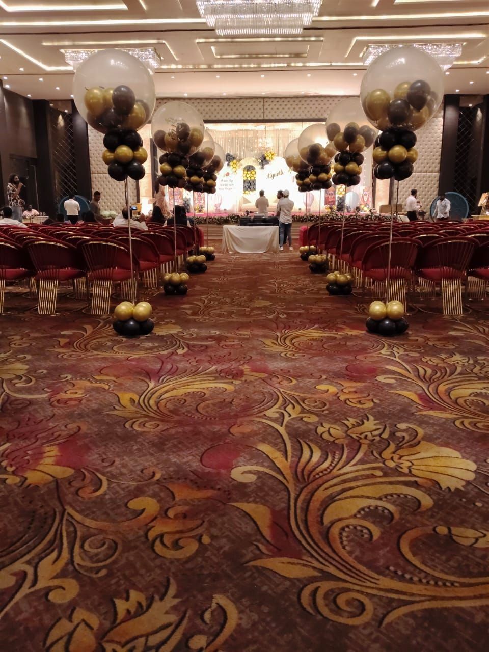 Black and gold balloon aisle decoration in a ballroom reception by Mayur Events Bilaspur